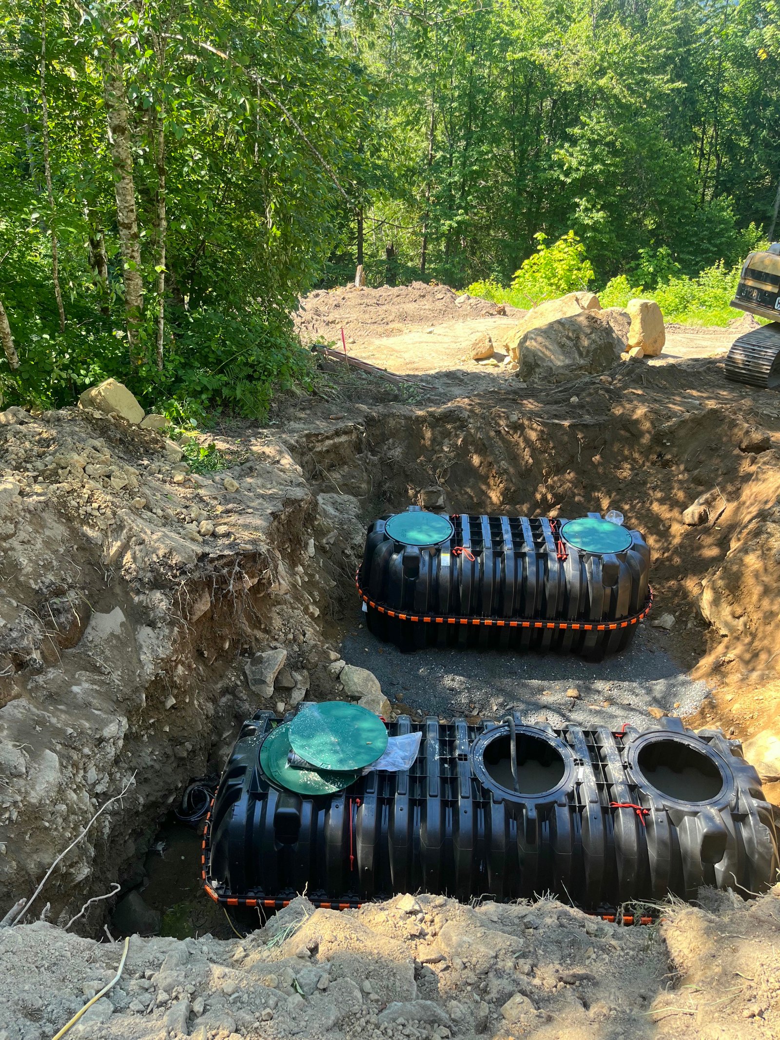 Two new septic tanks being set and leveled in an excavation pit by Bloomstrom Construction